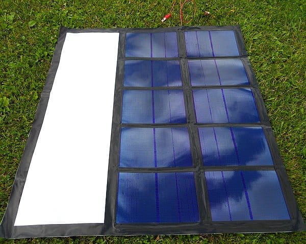 The foldable solar panel, perfect for your next boat tour, features a white section on the left and sits elegantly on the lush green grass.
